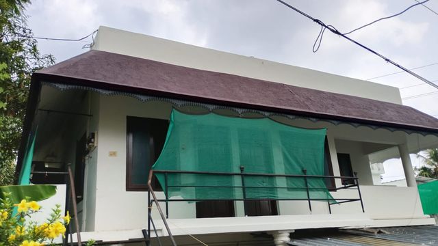 Front of the Ashraf Gents Hostel building with its upstairs balcony and green shade net, Kalamassery