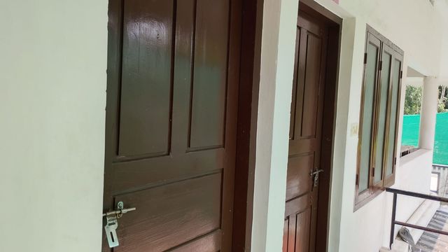 Corridor with wooden room doors at Ashraf Gents Hostel, Kalamassery